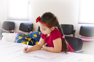 Young girl coloring in notebook.